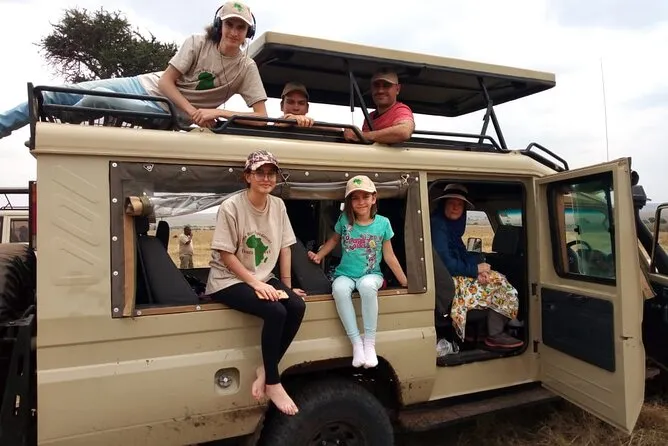 Open-top safari vehicle on a game drive in Nairobi National Park with wildlife visible against the city skyline — zoo in Nairobi Kenya